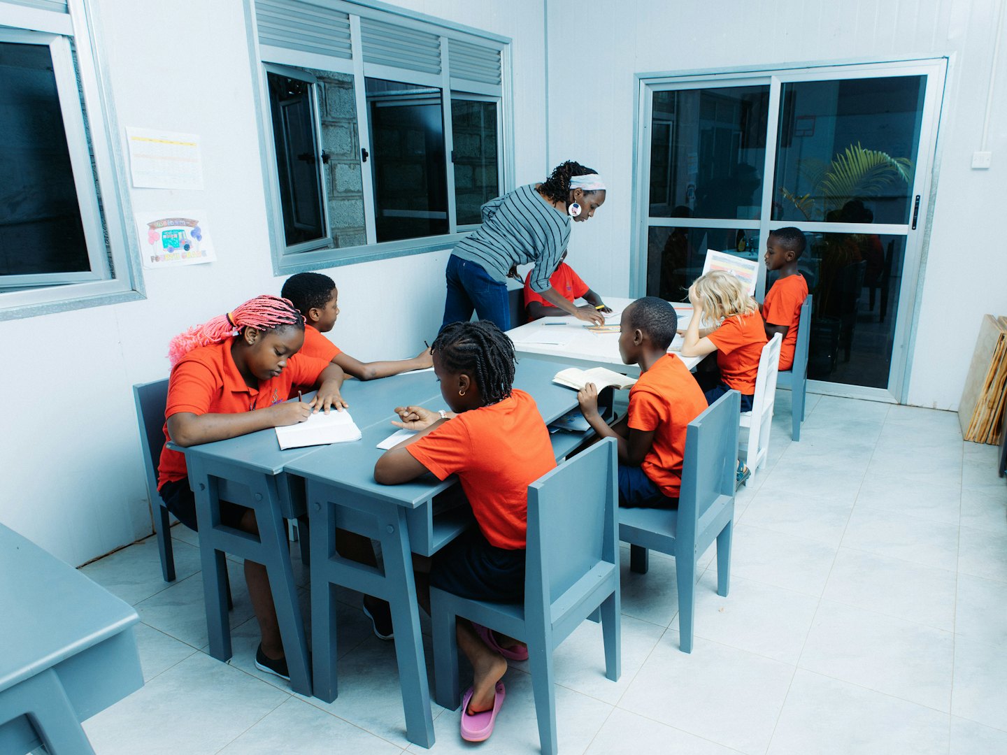 Teacher helps student at a table in a classroom.