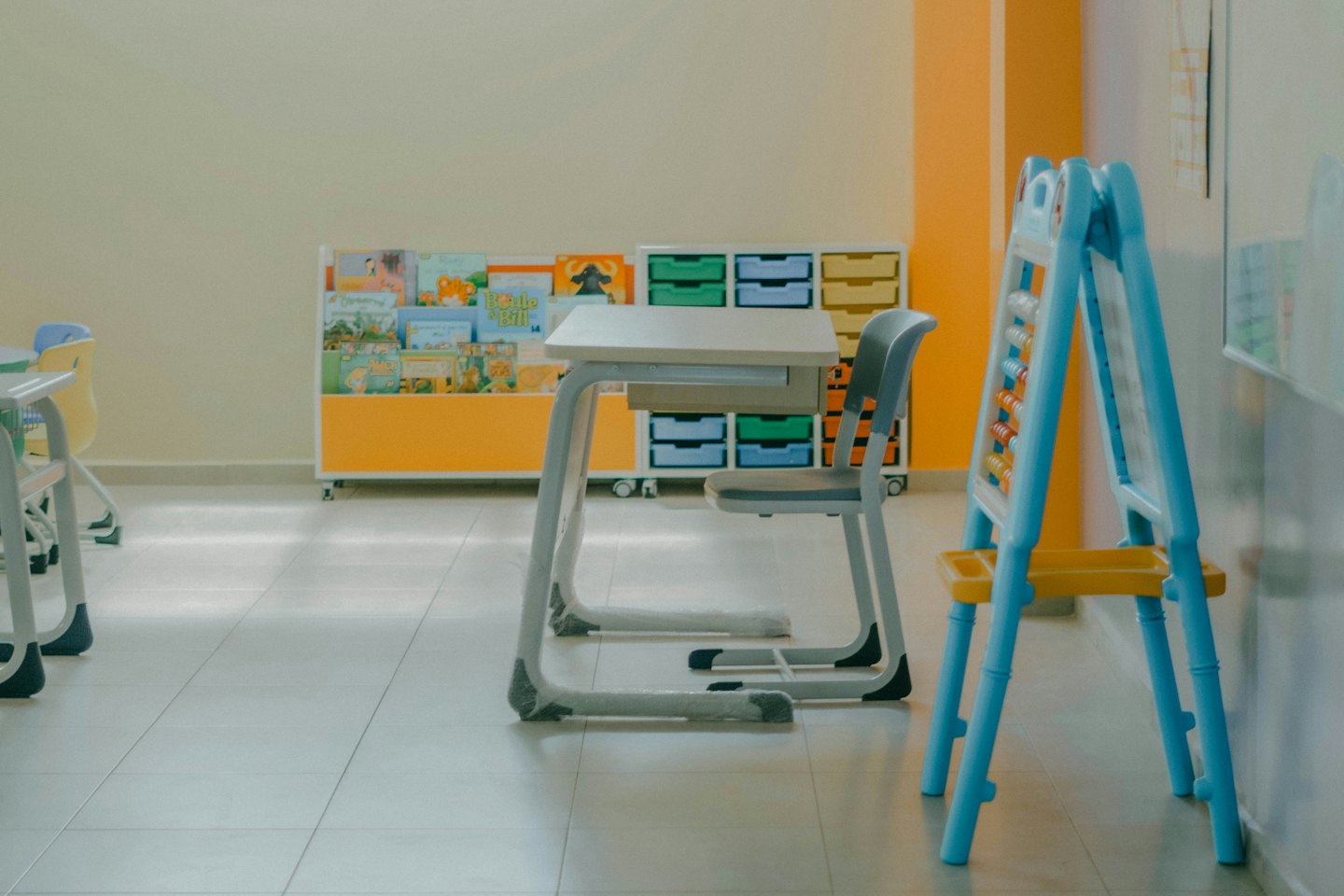Modern desk and chair in a bright classroom with colorful books.
